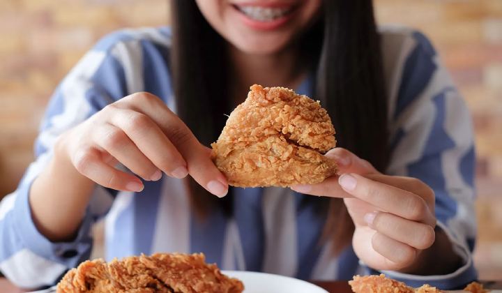 قیمت غذایی سینه مرغ؛ مزایا و بهترین روش مصرف آن 5 زنی در حال خوردن سینه مرغ سوخاری